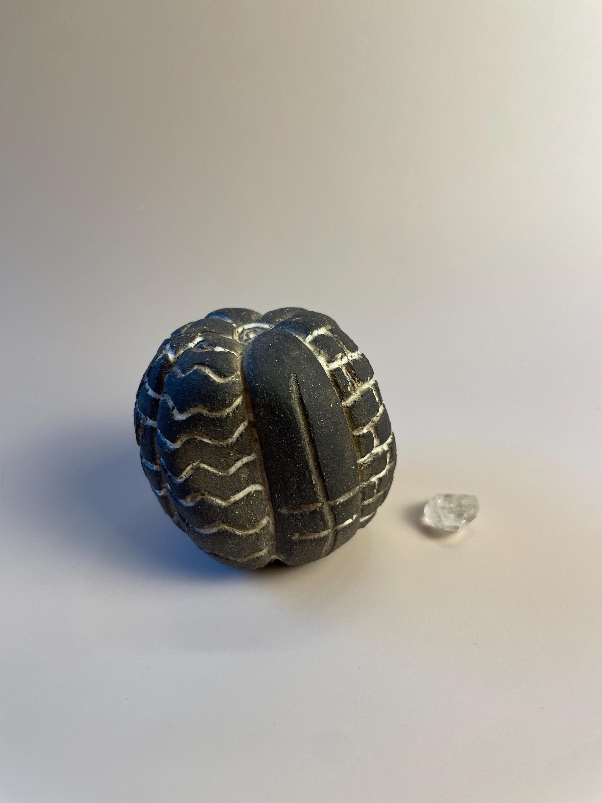 Handmade ceramic carved clay rattle with spiral and eye symbols