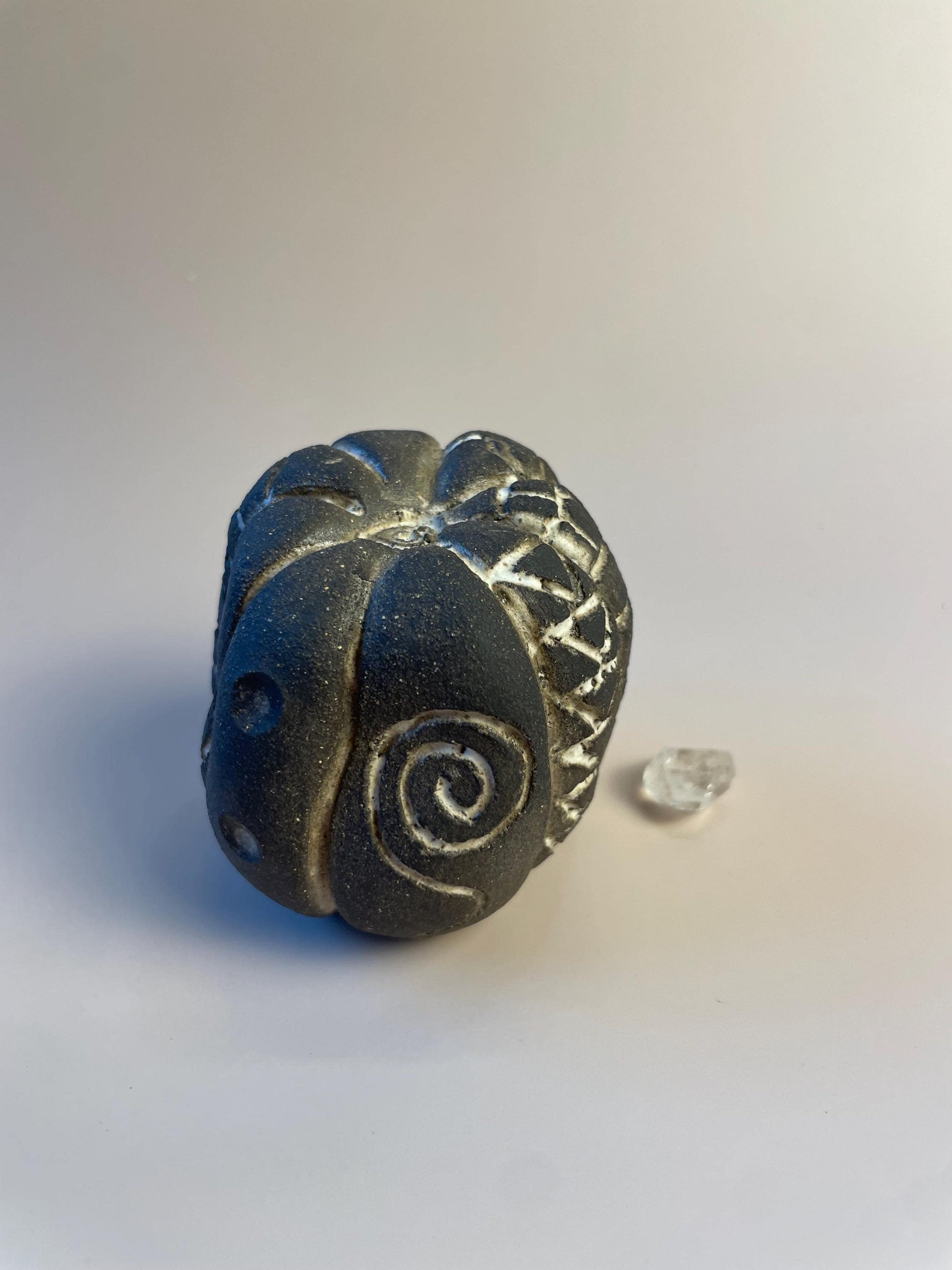 Handmade ceramic carved clay rattle with spiral and eye symbols