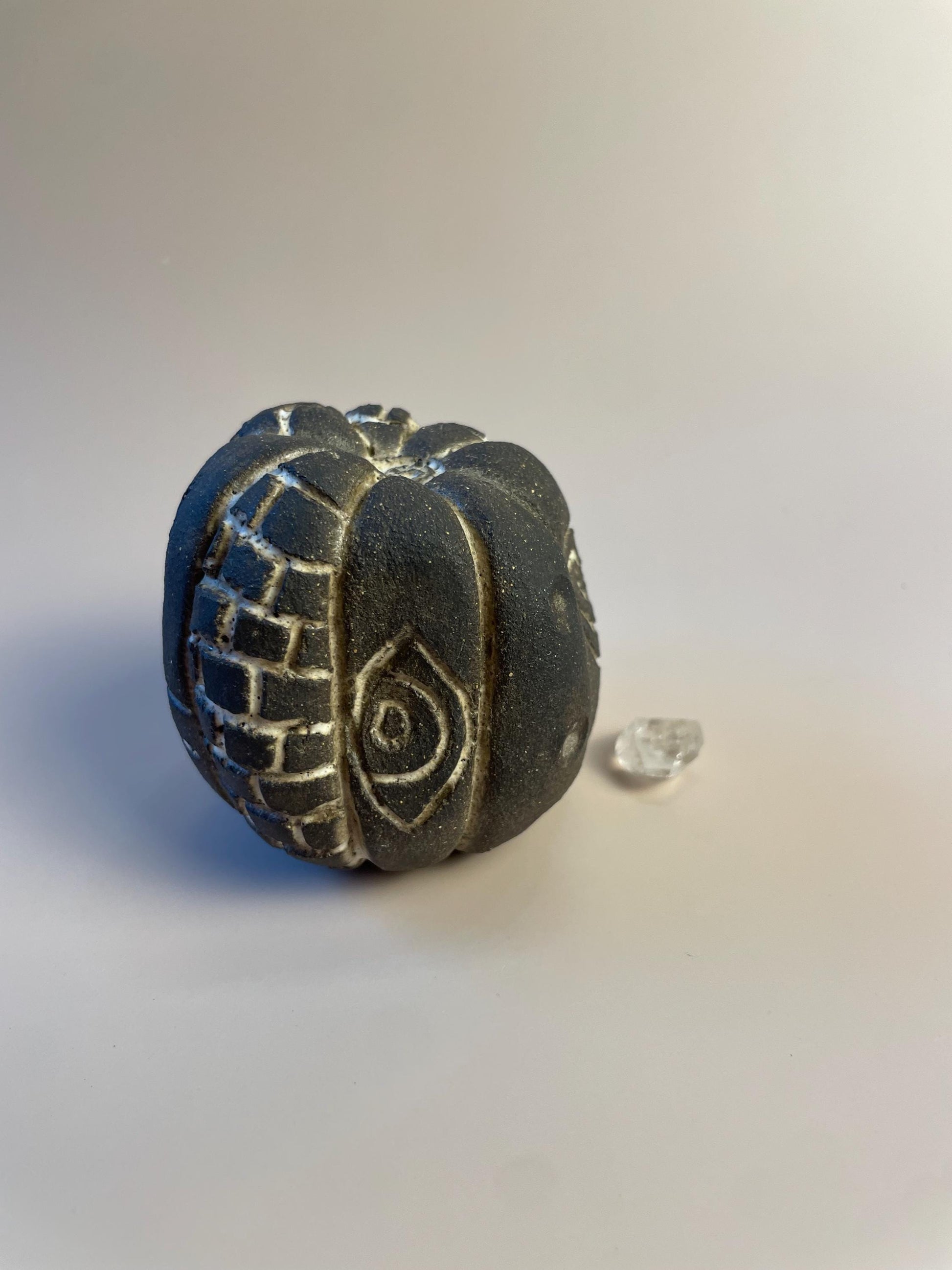 Handmade ceramic carved clay rattle with spiral and eye symbols