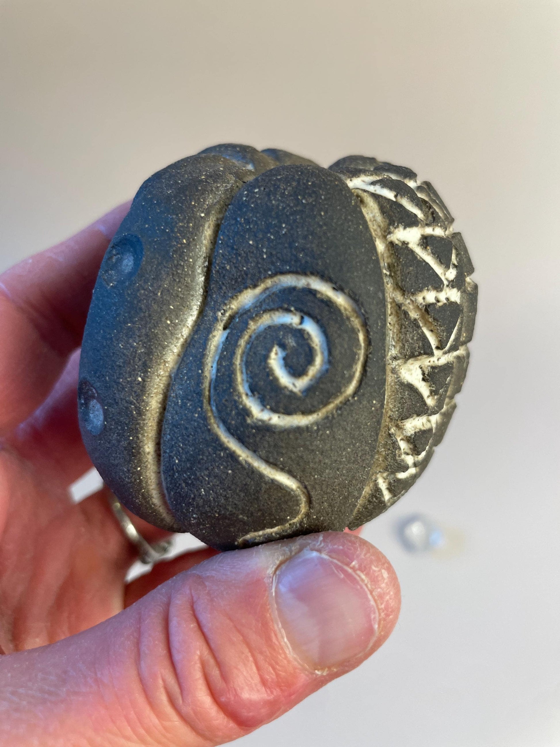 Handmade ceramic carved clay rattle with spiral and eye symbols
