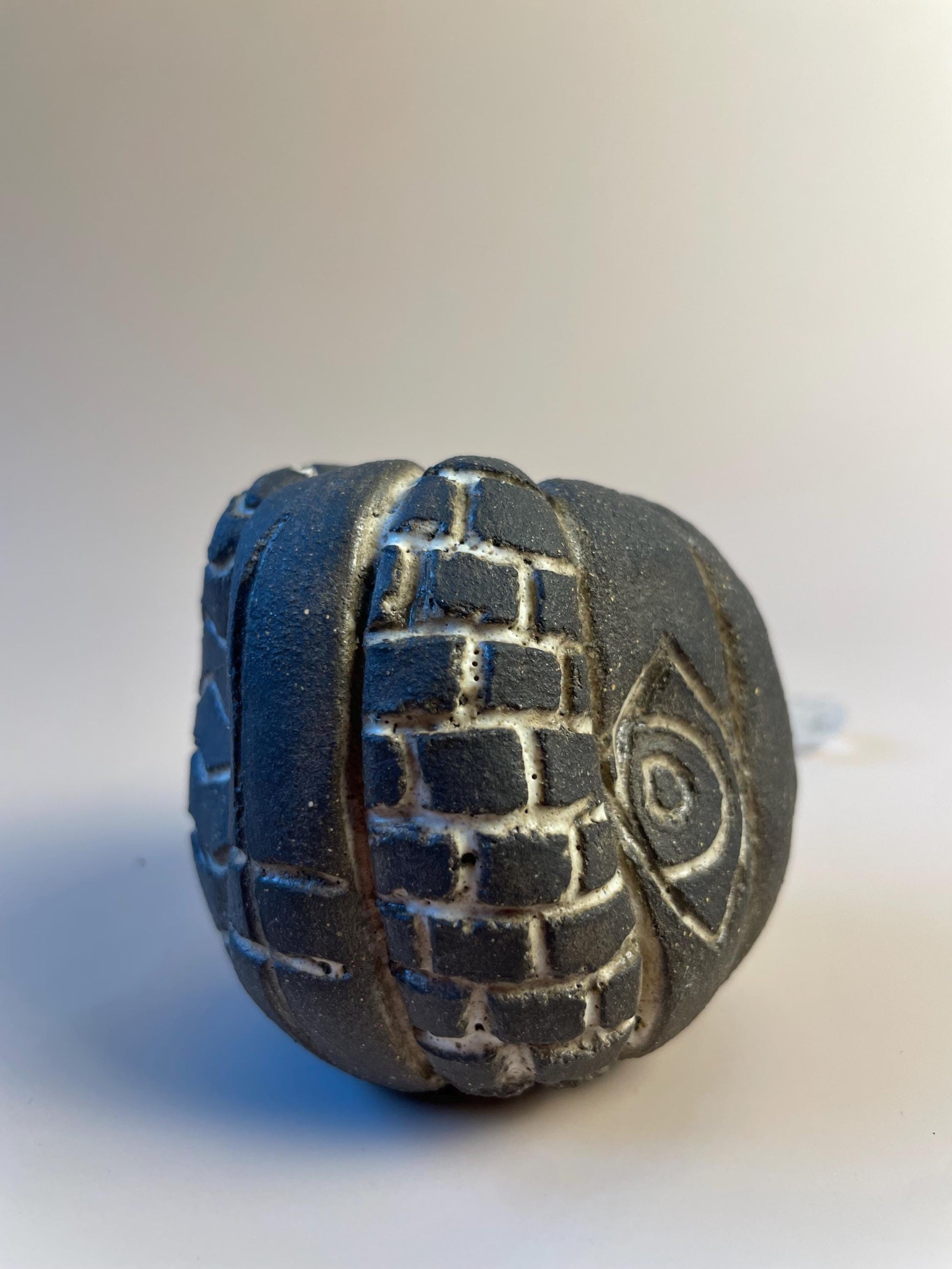 Handmade ceramic carved clay rattle with spiral and eye symbols