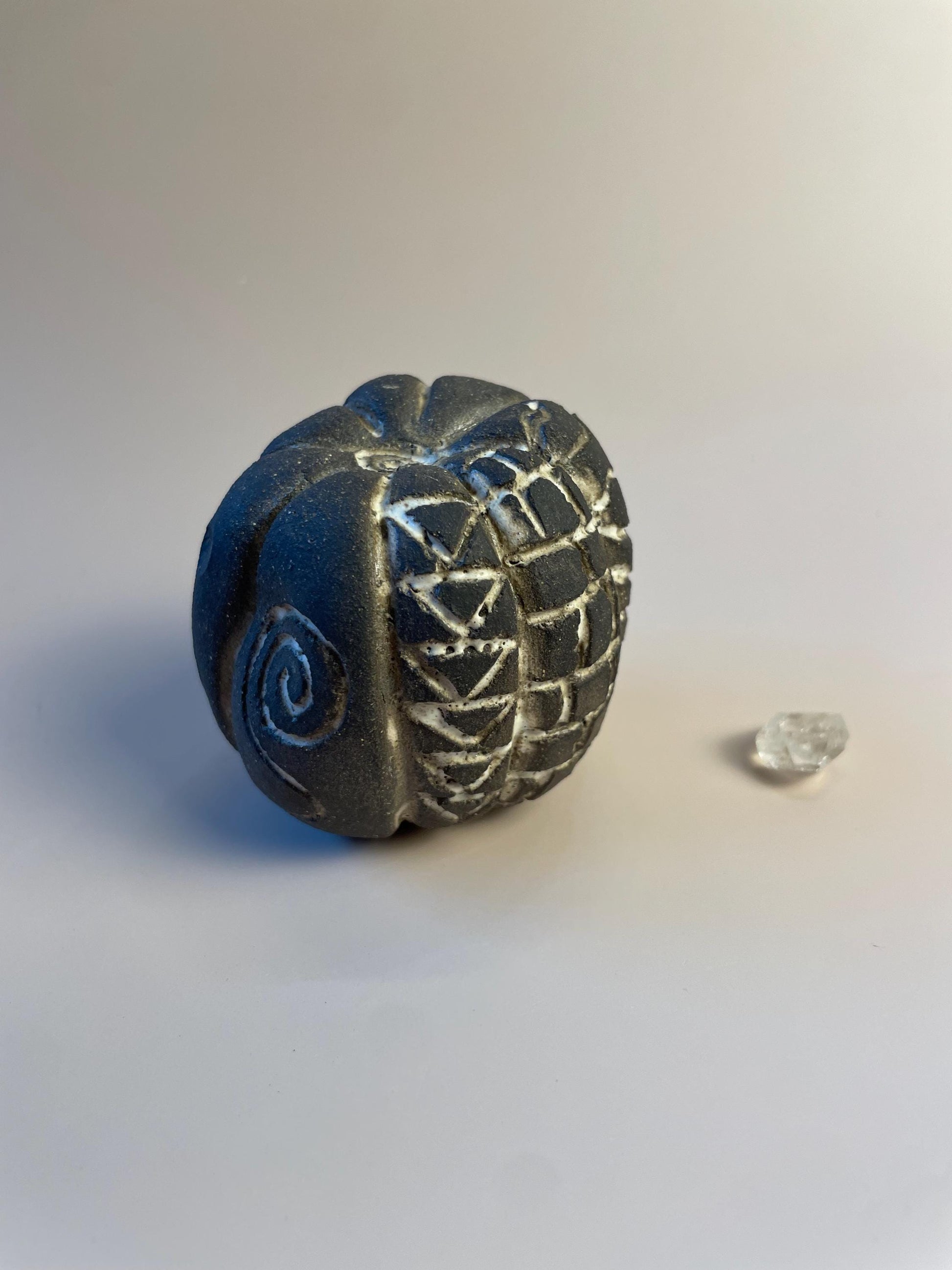 Handmade ceramic carved clay rattle with spiral and eye symbols