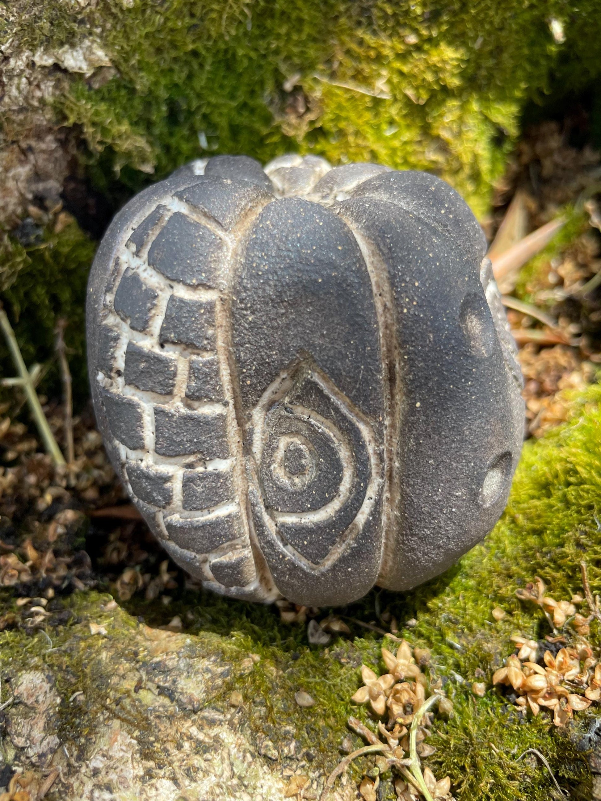 Handmade ceramic carved clay rattle with spiral and eye symbols