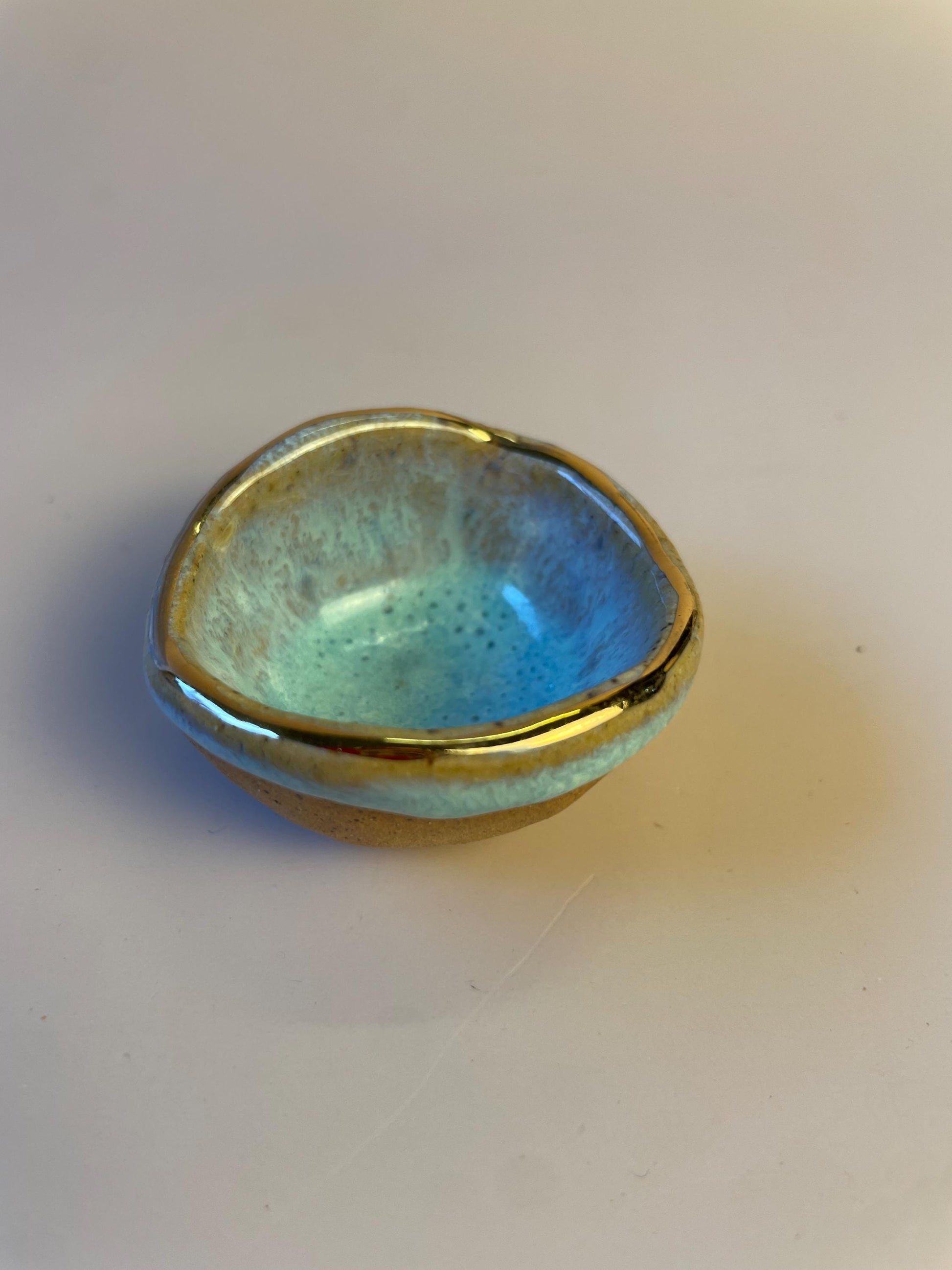 Tiny pinched ceramic bowl in aqua with gold rim