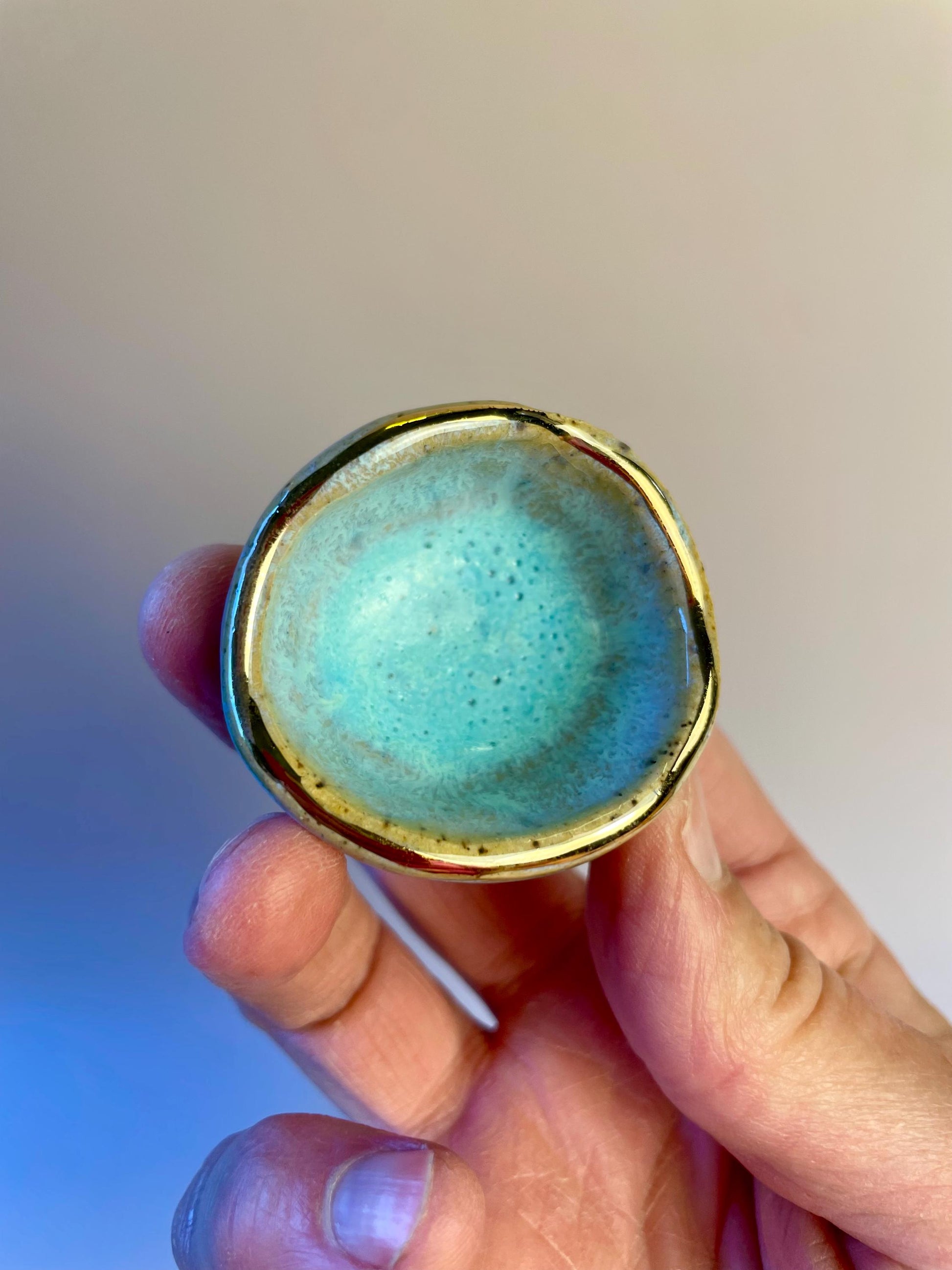 Tiny pinched ceramic bowl in aqua with gold rim