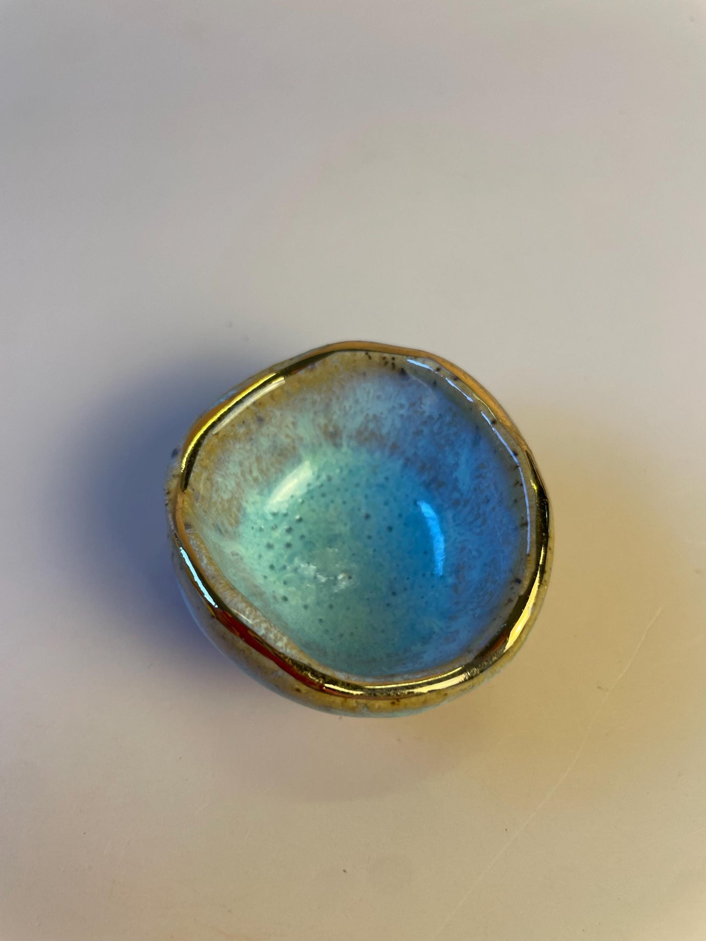 Tiny pinched ceramic bowl in aqua with gold rim
