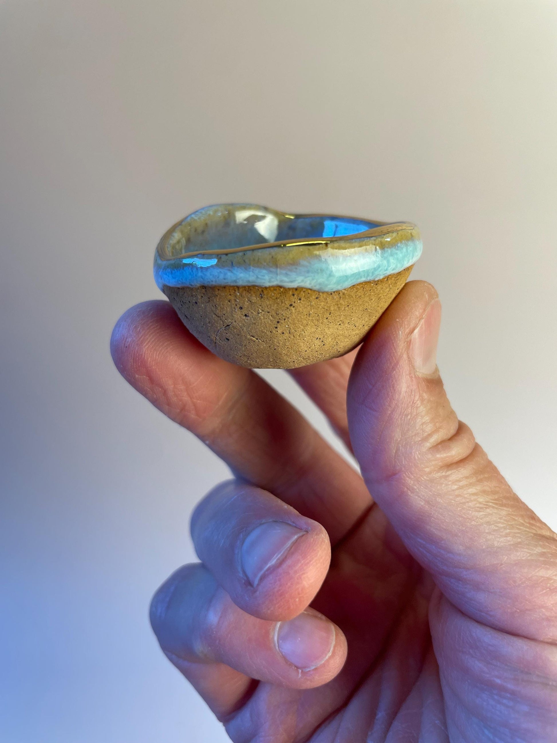 Tiny pinched ceramic bowl in aqua with gold rim
