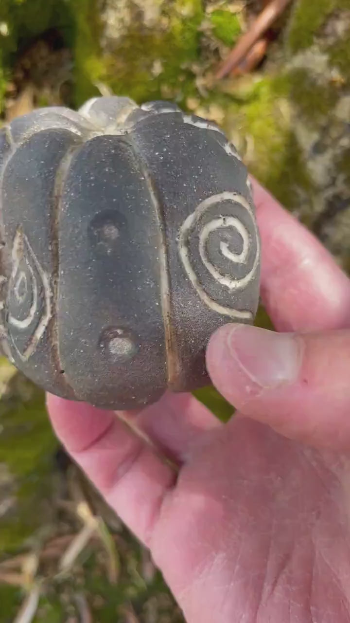 Handmade ceramic carved clay rattle with spiral and eye symbols