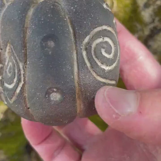 Handmade ceramic carved clay rattle with spiral and eye symbols